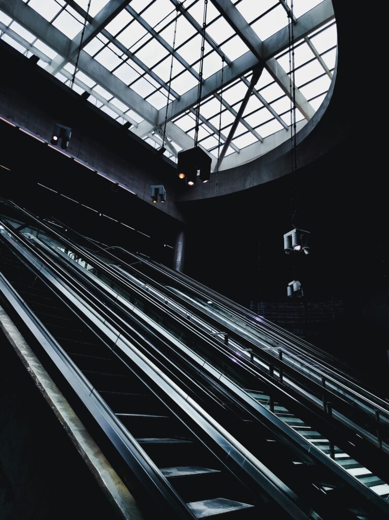 Futuristic escalator leading to a skylight in a modern urban subway station.
